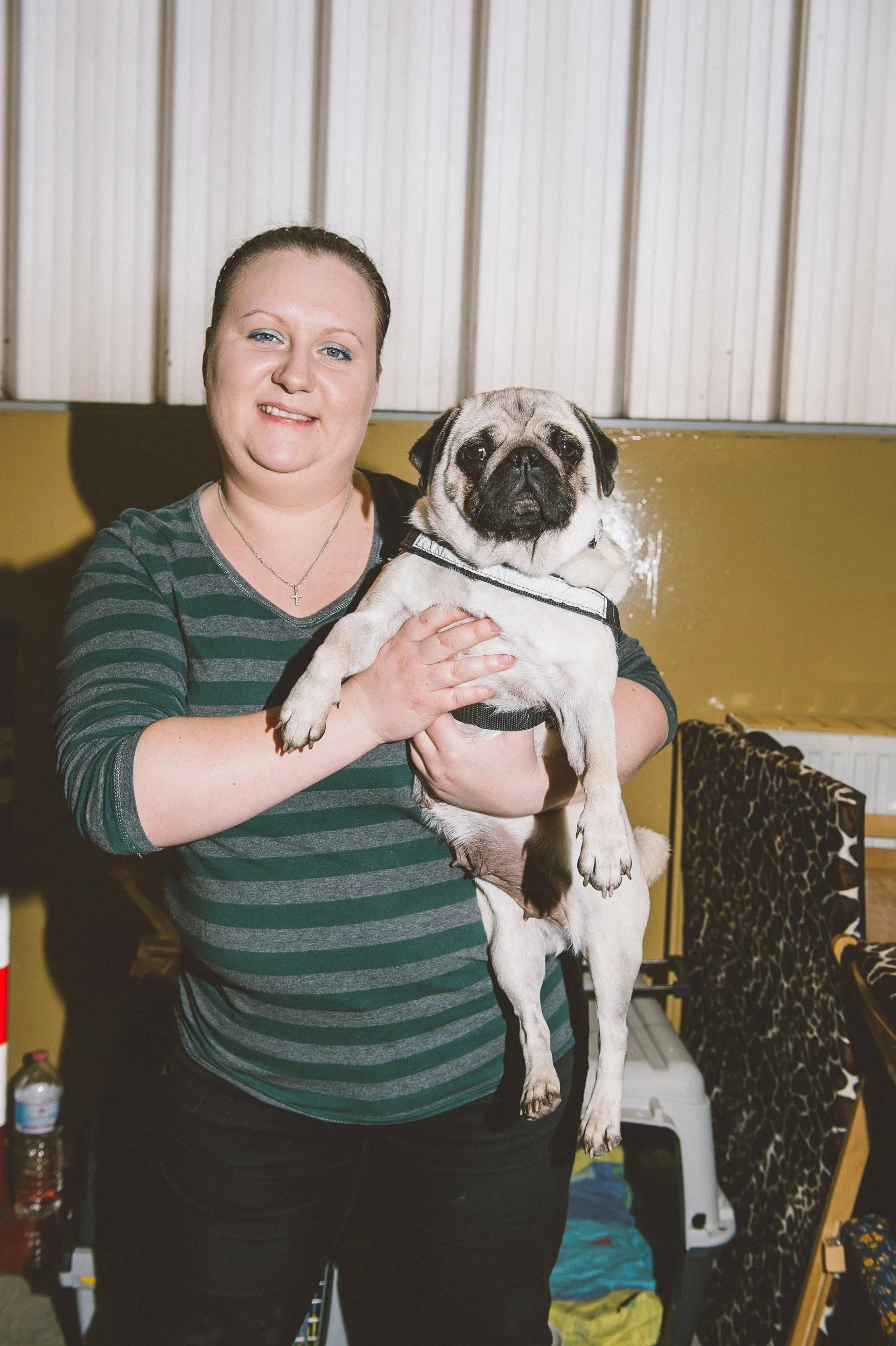 Smiling woman proudly holding her Pug for a portrait.